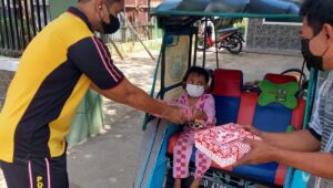 Personil Samsat Makassar memberikan makanan kepada tukang becak dan anaknya yang sedang mangkal menunggu penumpang