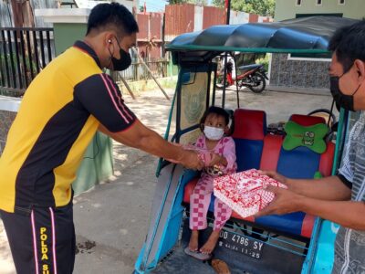 Personil Samsat Makassar memberikan makanan kepada tukang becak dan anaknya yang sedang mangkal menunggu penumpang